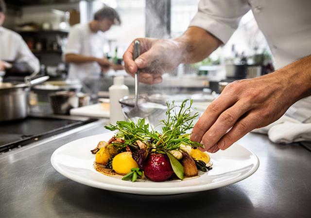 Köchin richtet ein saisonales Gericht in einer offenen Restaurantküche in Zürich an